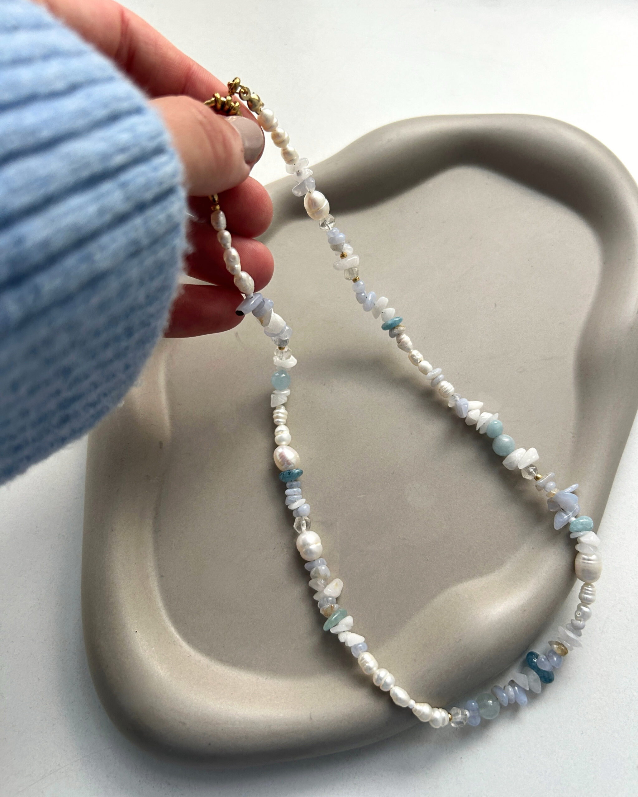 Frau hält blaue kette in der hand