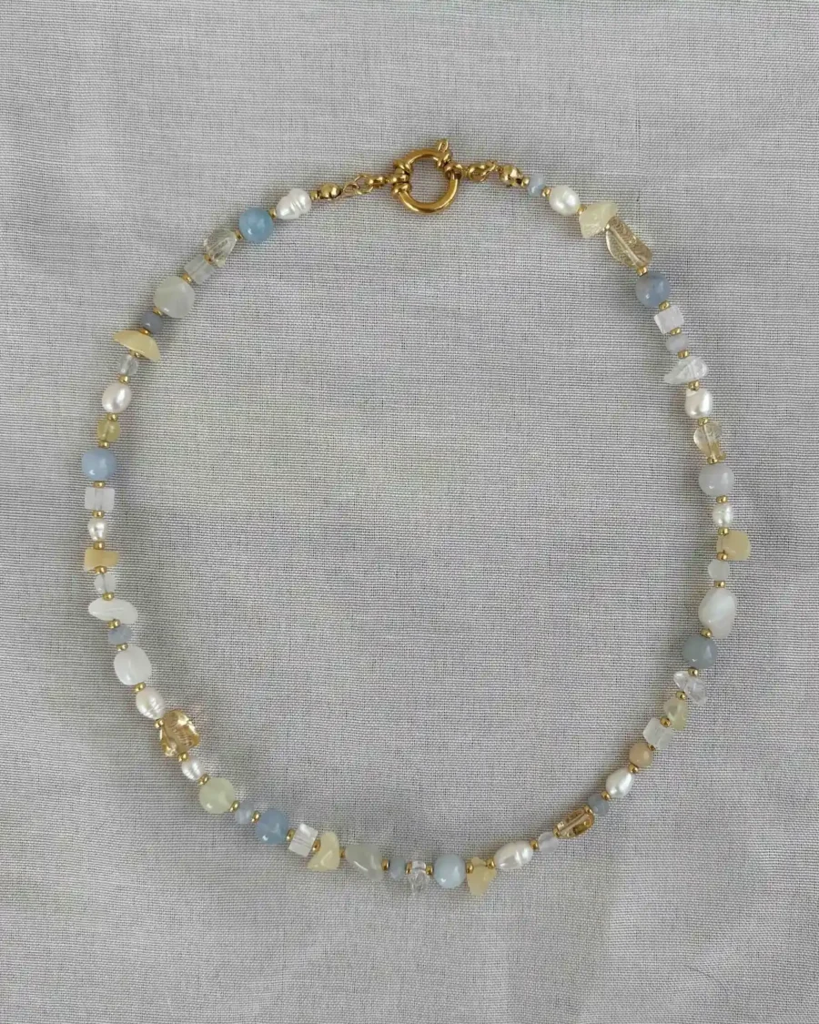 blaue Kette liegt auf grauem stoff