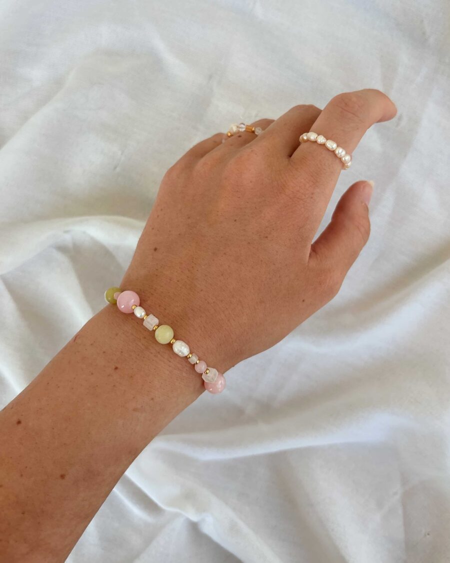 Hand trägt hellrosa armband auf weißem hintergrund
